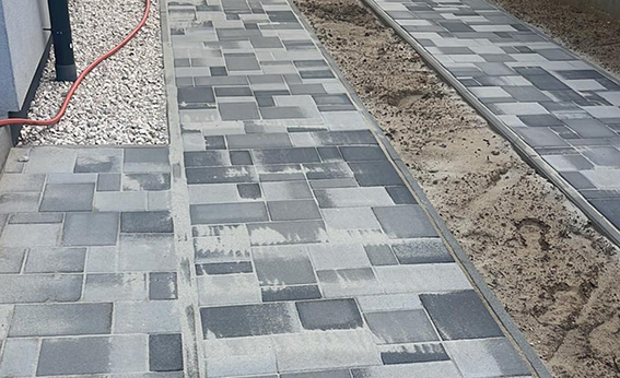 Szürke kétszínű térkő járda hézagolás közben